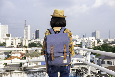 Rear view of woman looking at cityscape against sky