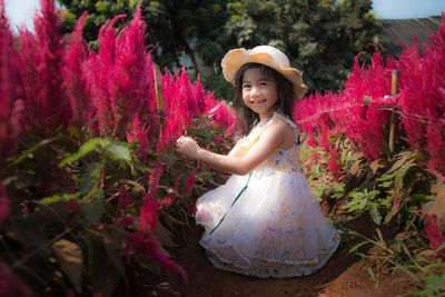 Portrait of smiling woman with pink flowers against plants