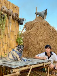 Portrait of woman sitting with dog by hay 