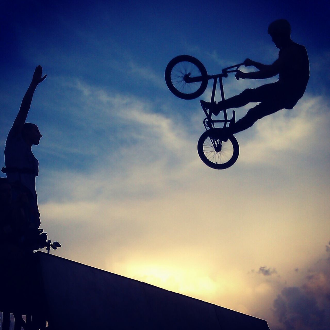 low angle view, sky, silhouette, men, leisure activity, cloud - sky, lifestyles, bicycle, stunt, transportation, cloud, dusk, sunset, mid-air, outdoors, extreme sports, street light