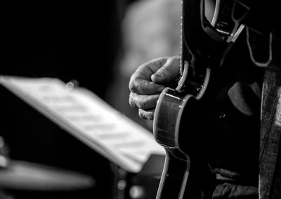 Midsection of man playing guitar at music concert