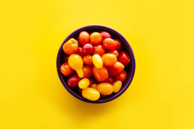 Directly above shot of tomatoes in bowl against yellow background