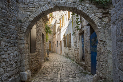 View of old narrow cobblestone street with arc and buildings in ancient town of bale istria, croatia