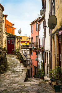 View of narrow street between old residential building against cloudy sky