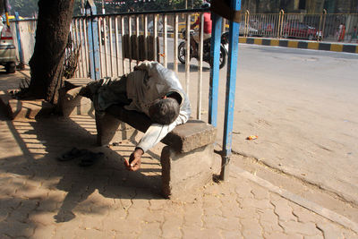 Man sitting on street in city