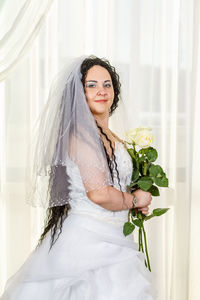 Portrait of woman standing against white wall