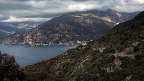 Scenic view of mountains and sea against cloudy sky