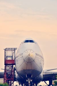 Airplane on airport runway against sky during sunset