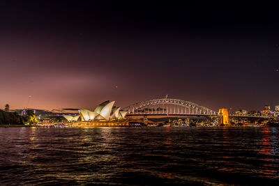 Illuminated bridge over river against sky at night