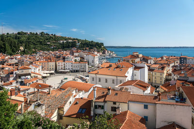 High angle view of townscape by sea against blue sky