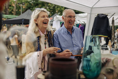 Cheerful senior couple shopping at market in city