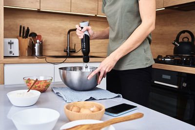 Woman in the kitchen cooking a cake. hands beat the dough with an electric mixer