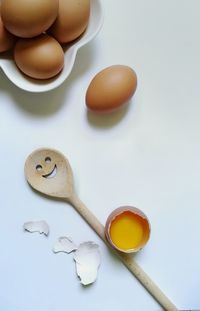 Eggs and wooden spoon on white background