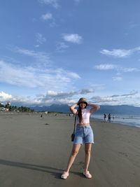 Rear view of woman standing on beach against sky
