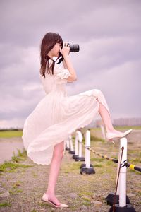 Woman photographing against sky