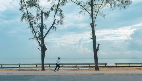 Young woman exercising against clouds and sky 