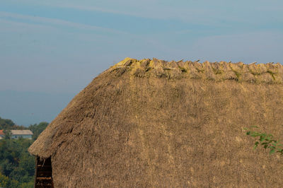 A white with a thatched roof and blue sky background