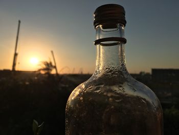 Close-up of water bottle against sky during sunset