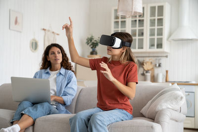 Interested teenage girl uses vr headset to visit metaverse or watch 3d movies from comfort home
