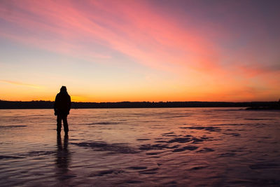 Silhouette man standing on beach against sky during sunset