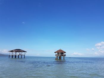 Lifeguard hut in sea against clear blue sky