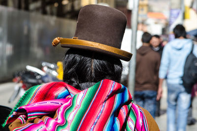 Rear view of person with colorful scarf and hat on street