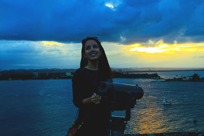Portrait of young woman photographing at sunset