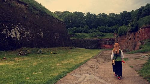 Full length of young woman standing on grass against trees