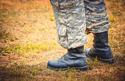 Man stands in military trousers and boots, ankle boots on the ground, the filter