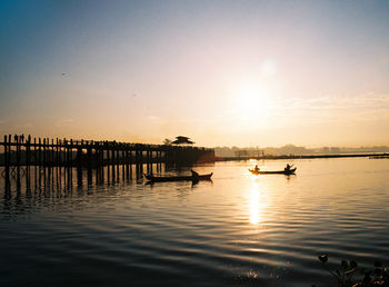 Silhouette boats in sea against sky during sunset