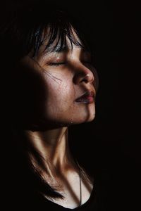 Close-up of woman sweating against black background
