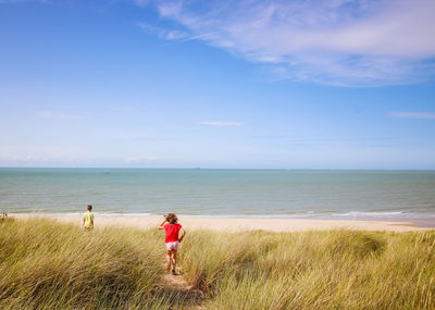 Siblings playing at beach against sky