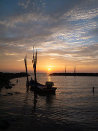 Silhouette sailboats in sea against sky during sunset