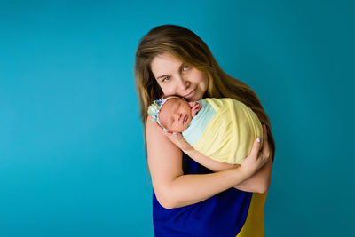 Portrait of woman embracing daughter against blue background