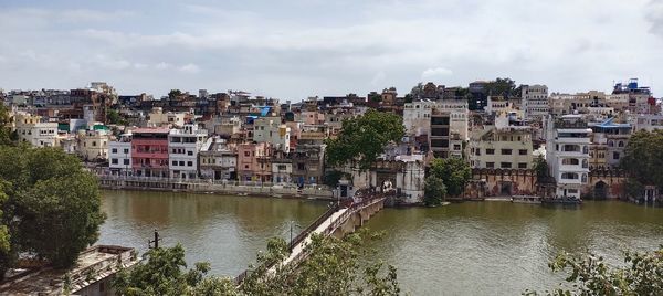 Nature theories- lake amidst buildings in town against sky