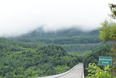 Road amidst trees and mountains against sky