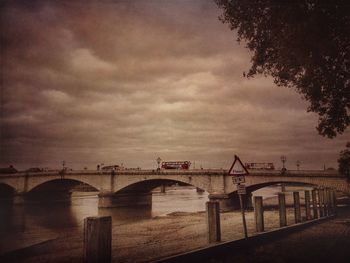 Bridge over river against cloudy sky