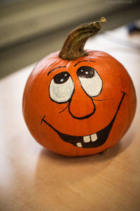 Cropped hand holding pumpkin on table