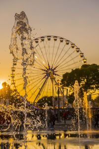 Illuminated ferris wheel against clear sky