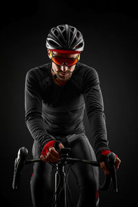 Determined athlete riding bicycle against black background