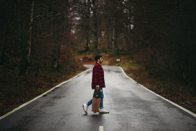 Rear view of man walking on road in forest