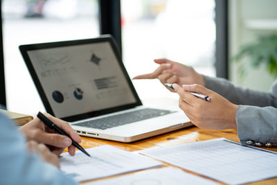 Midsection of woman using laptop on table