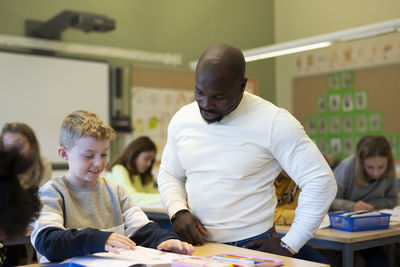 Teacher helping boy in classroom