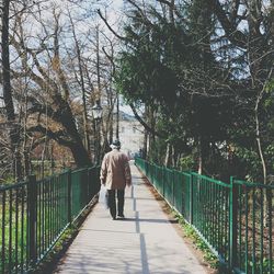 Rear view of man walking on footbridge