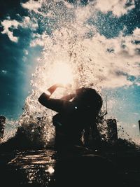 Rear view of woman standing in sea against sky