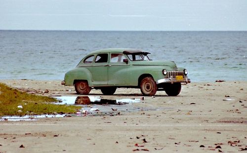 Toy car on beach against clear sky