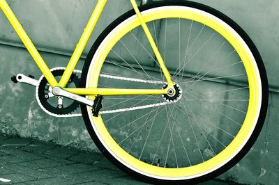 Close-up of bicycle wheel against yellow wall