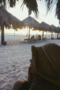 Close-up of woman in hat relaxing at beach during sunset