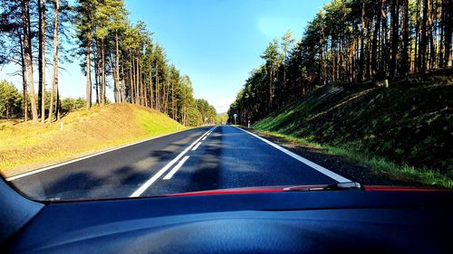 Road amidst trees seen through car windshield