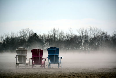 Chairs on field against sky